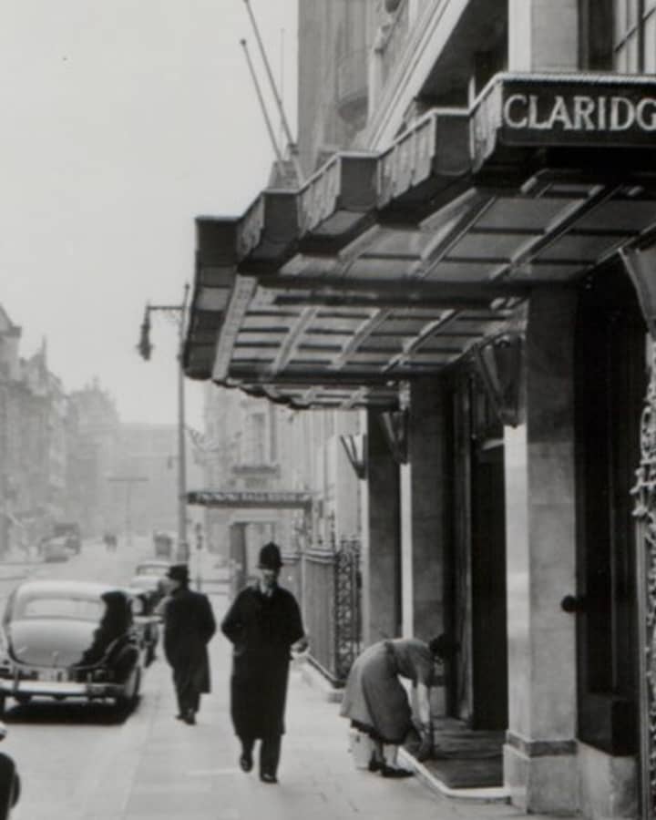 Historic black-and-white photo of Claridge’s Hotel entrance, London, capturing a classic scene with vintage cars and pedestrians