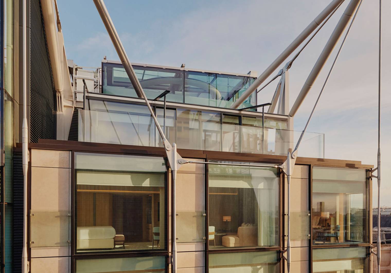 Exterior of The Emory, showcasing modern glass facade, elegant interiors, and striking architectural supports under a clear blue sky