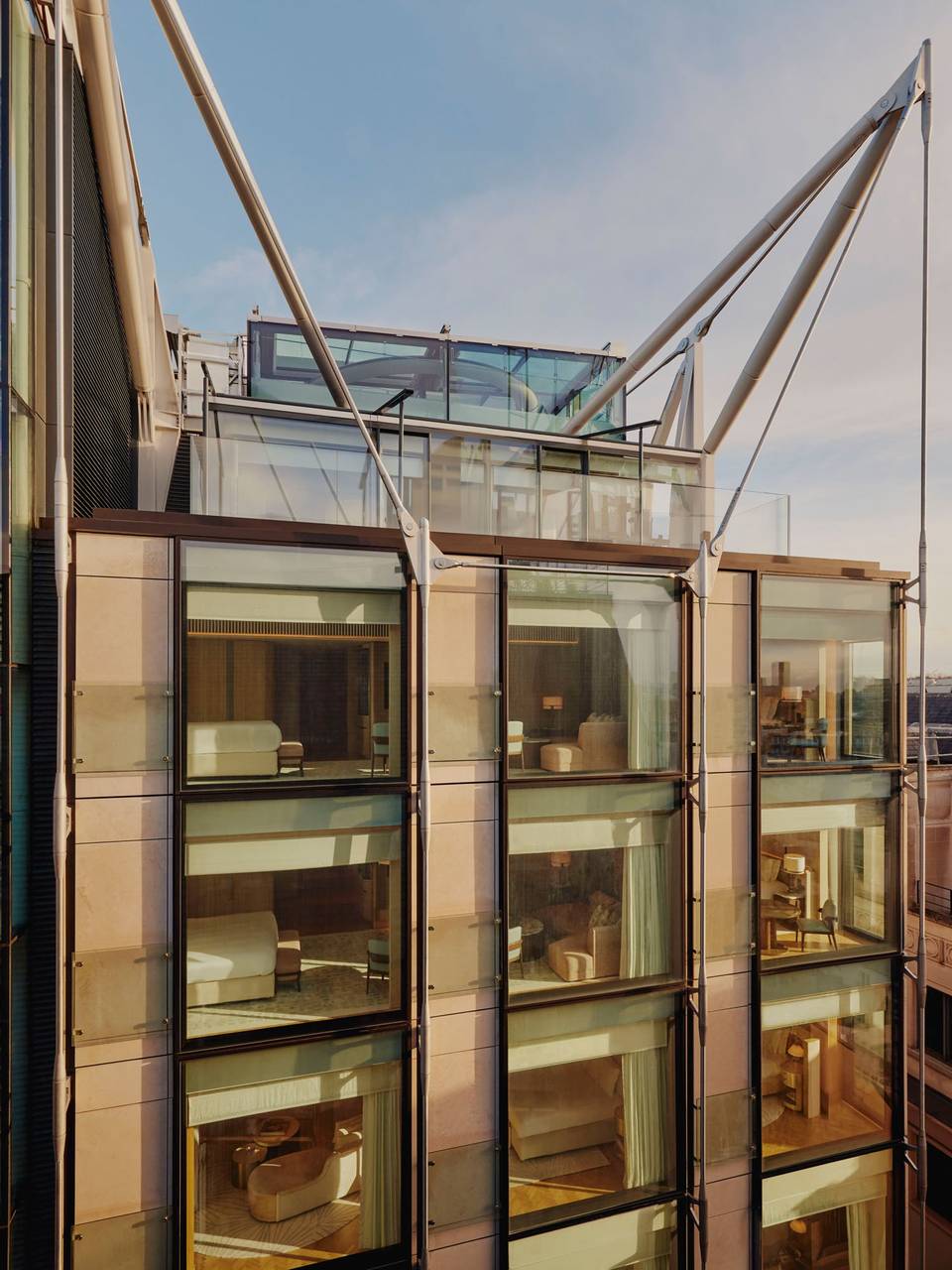 Exterior of The Emory, showcasing modern glass facade, elegant interiors, and striking architectural supports under a clear blue sky