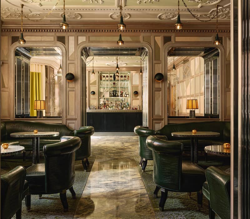 Opulent bar with mirrored accents, crocodile-patterned leather seating, marble flooring, and a sleek counter framed by luxurious decor.
